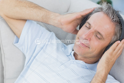 Man lying on couch listening to music