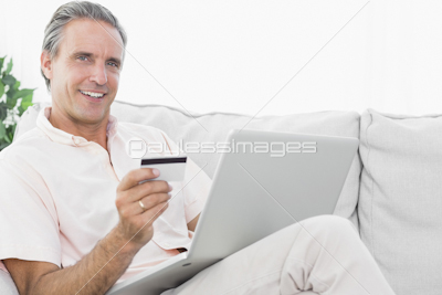 Man on his couch using laptop for online shopping