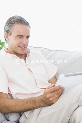 Man relaxing on his couch using tablet pc