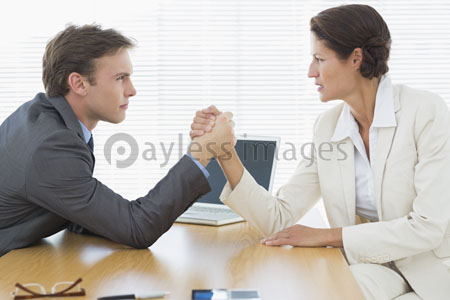 Serious business couple arm wrestling of an office desk
