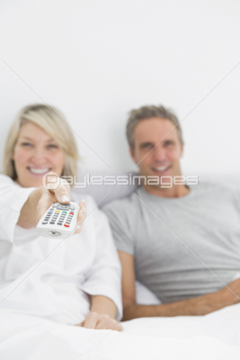 Smiling couple watching tv in bed