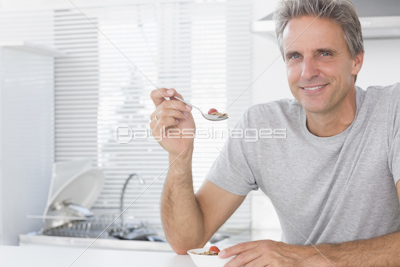 Smiling man having glass of orange juice in kitchen