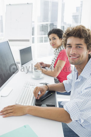 The accidental couple is using the computer in the office.