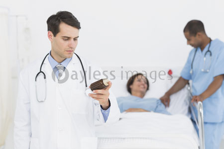 The doctor holds the bottle of a tablet with the patient in the hospital.