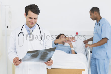 The doctor is inspecting X-rays with the patient in the hospital.