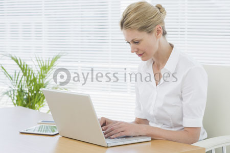 The female businessman is using laptop at the desk.