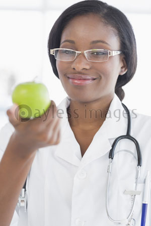 The portrait of smiling female doctor holding an apple