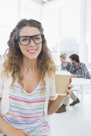 The,woman,holds,the,disposable,coffee,cup,with,the,coworker,in,a,background.