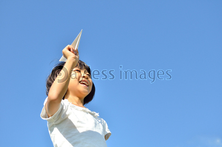 青空に紙飛行機を飛ばす女の子 ストックフォトの定額制ペイレスイメージズ