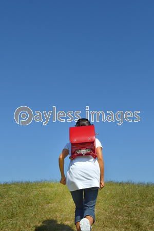 青空で走る小学生の女の子 後姿 ストックフォトの定額制ペイレスイメージズ