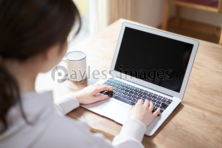 リビングでパソコン作業をするアジア人女性の後ろ姿 商用利用可能な写真素材 イラスト素材ならストックフォトの定額制ペイレスイメージズ