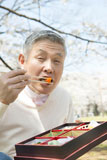 桜の下で食事をするシニア男性