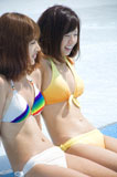 プールサイドに座る水着姿の女性2人