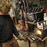 Metalsmith+heating+metal+in+forge.