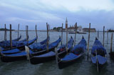 Array+of+gondolas+docked+at+a+canal+in+Venice%2C+Italy