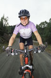 Woman+outdoors+on+trails+riding+bicycle+and+smiling+%28selective+focus%29