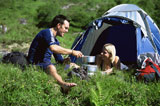 Couple+outdoors+at+campsite+with+pots+smiling+%28selective+focus%29