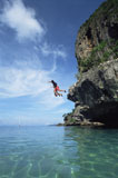 Couple+outdoors+jumping+off+cliff+into+ocean