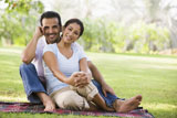 Couple+sitting+outdoors+in+park+smiling+%28selective+focus%29