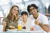 Family+at+restaurant+eating+dessert+and+smiling+%28selective+focus%29