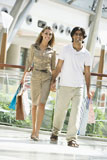 Couple+walking+in+mall+holding+hands+and+smiling+%28selective+focus%29
