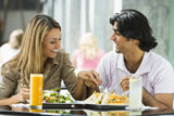 Couple+at+restaurant+eating+and+smiling+%28selective+focus%29