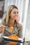 Woman+at+restaurant+eating+spaghetti+and+smiling+%28selective+focus%29