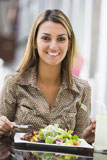 Woman+at+restaurant+eating+salad+and+smiling+%28selective+focus%29