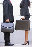 Two+businesspeople+standing+outdoors+holding+briefcases