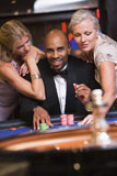 Three+people+in+casino+playing+roulette+smiling+%28selective+focus%29