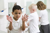 Students+in+bathroom+at+sinks+washing+hands+with+one+holding+up+soapy+hands+%28selective+focus%29