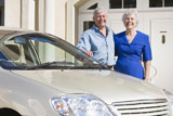 Senior+couple+standing+with+their+car+outside+their+home