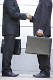 Two+businessmen+holding+briefcases+outdoors+shaking+hands