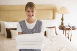 Maid+holding+towels+in+hotel+room+smiling