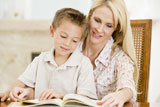 Woman+and+young+boy+reading+book+in+dining+room+smiling