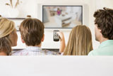 Family+in+living+room+with+remote+control+and+flat+screen+television