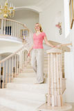Woman+coming+down+staircase+in+luxurious+home+smiling