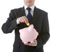 Businessman+Putting+Coin+Into+Piggy+Bank