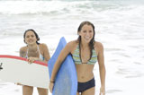 Close-up+of+two+young+women+carrying+surfboards