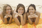 Portrait+of+three+young+women+lying+on+a+beach+towel+and+smiling