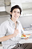 Close-up+of+a+young+man+holding+a+plate+of+salad+and+smiling
