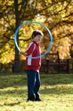 Boy+playing+with+a+plastic+hoop+in+a+park