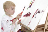 Toddler+boy+in+big+white+shirt+covered+in+paint+at+easel.+American+blonde+caucasian+boy.+Shot+over+white+background.