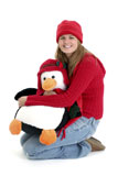 Teen+girl+in+red+jacket+and+hat+holding+a+large+toy+penquin.+Shot+in+studio+over+white.