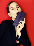 woman+in+suit+against+red+background+eating+chocolate