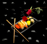 assorted+sushi+plate+with+red+rose+on+black+pebbles+over+black+background+