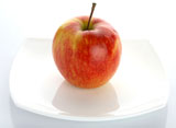 The+ripe+red+apple+lays+on+a+white+plateThe+ripe+red+apple+lays+on+a+white+plate