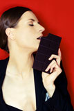 woman+in+suit+against+red+background+eating+chocolate