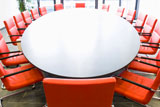 Meeting+room+with+red+chairs+and+oval+conference+table%2C+Focus+on+the+chair+in+the+foreground+