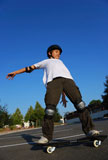 Boy+balancing+the+skateboard+shown+against+the+blue+sky+